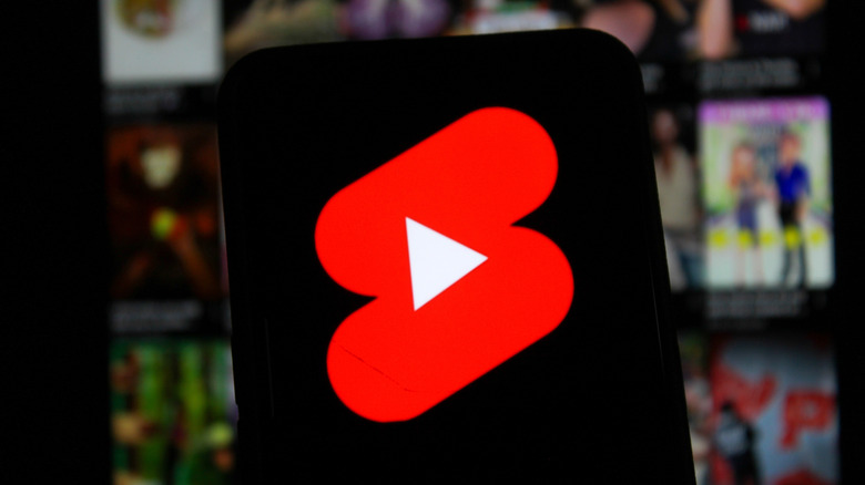 youtube shorts logo on black smartphone screen, video images blurred in background