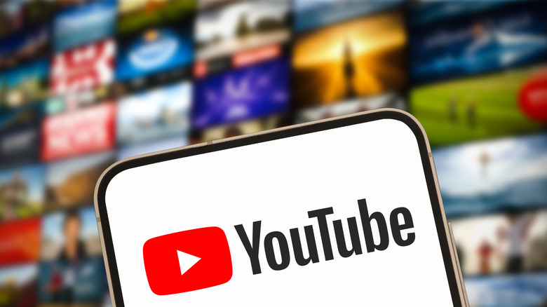 YouTube logo on smartphone with video icons in background