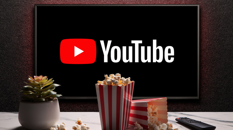 The YouTube logo shown on a TV with items like popcorn and a remote in the foreground.