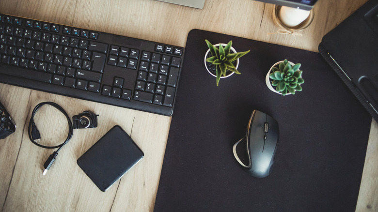 Mouse and keyboard on a desk with a medium-sized mouse pad.