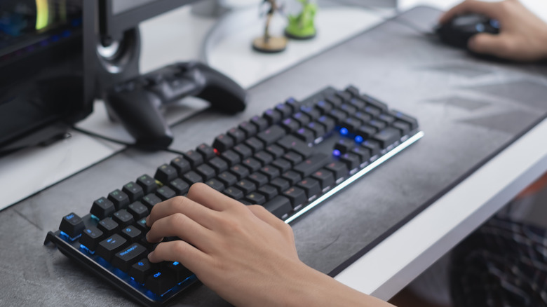 A person using a gaming keyboard and mouse on a mouse mat