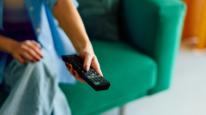 Someone holding out a remote to adjust display settings on a TV.
