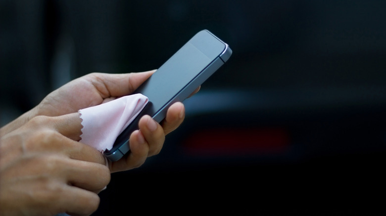 Close up of someone cleaning a smartphone display with a microfiber cloth.